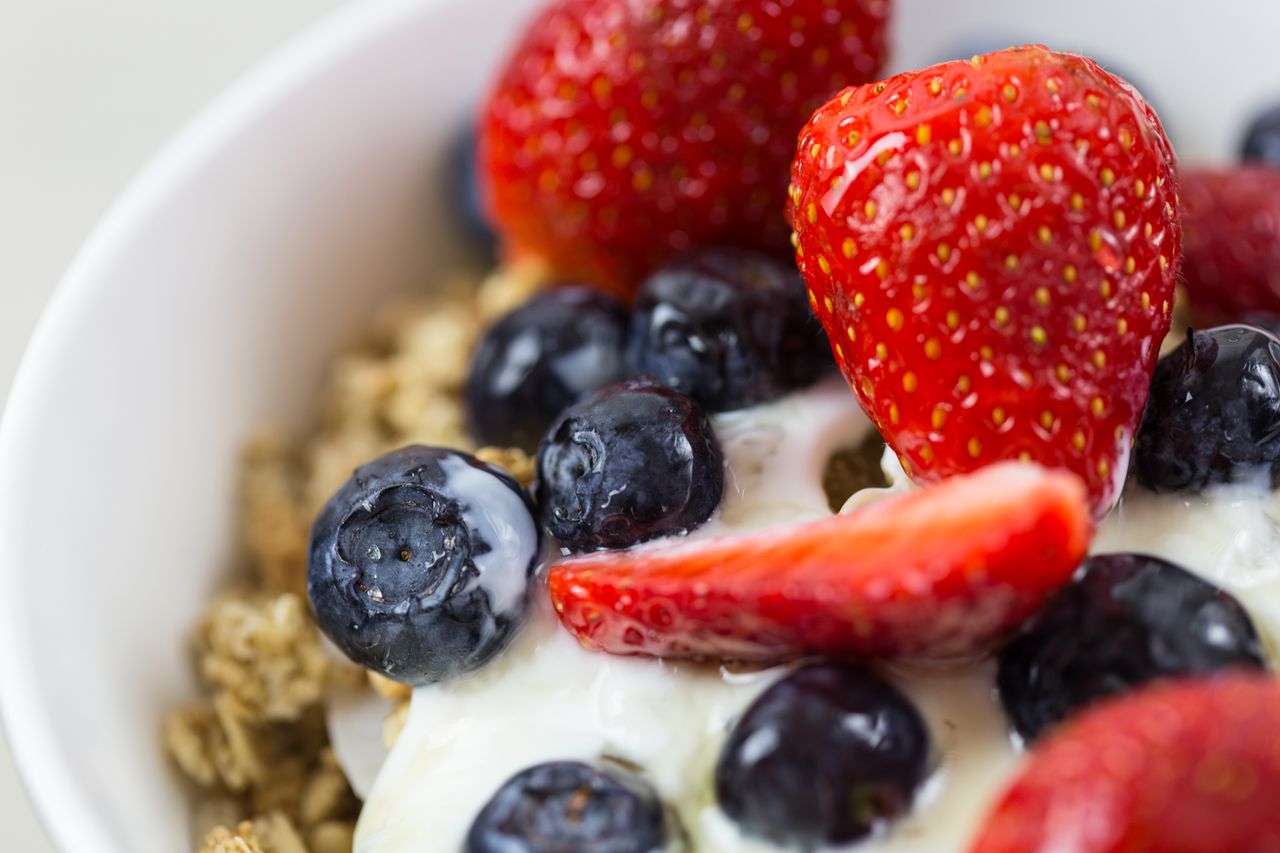 about-us Close-up of fresh blueberries and strawberries on yogurt with granola.
